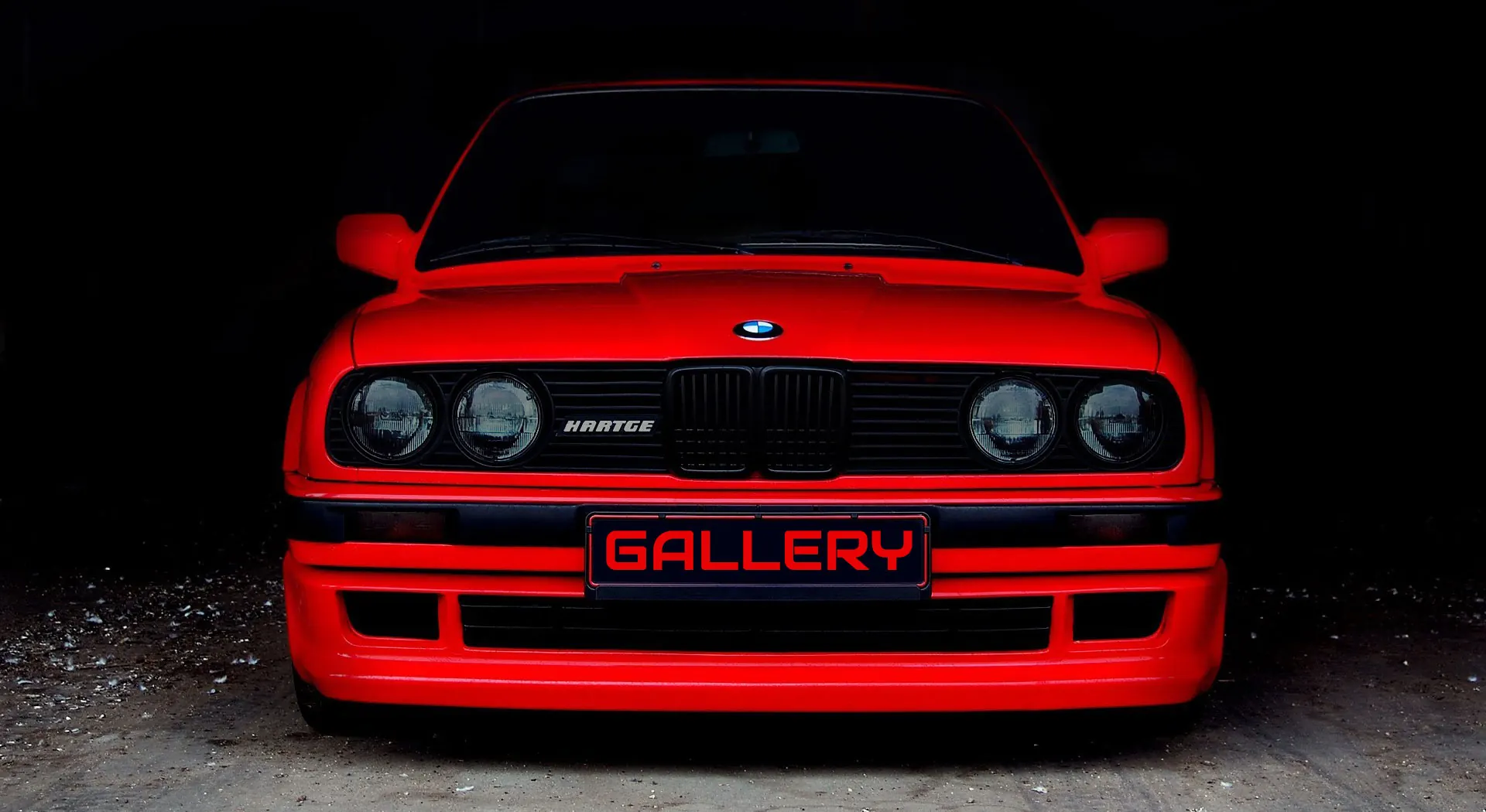 Glossy red BMW E30 shot head-on in a dark studio, showroom-ready after detailing